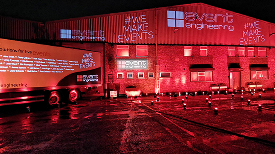 Photo of a warehouse and lorry taken in red light. The building is branded with "event engineering". 